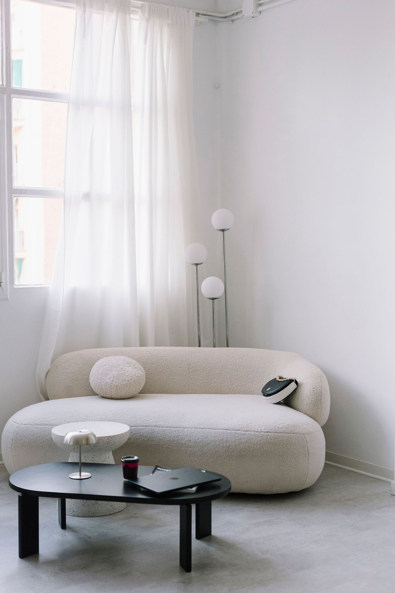 Bouclé chaise sofa beside sheer curtains