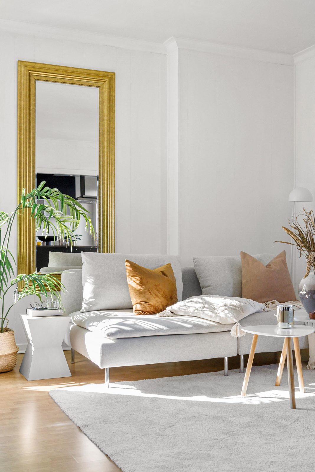 Light grey textured fabric sofa beside a gold mirror